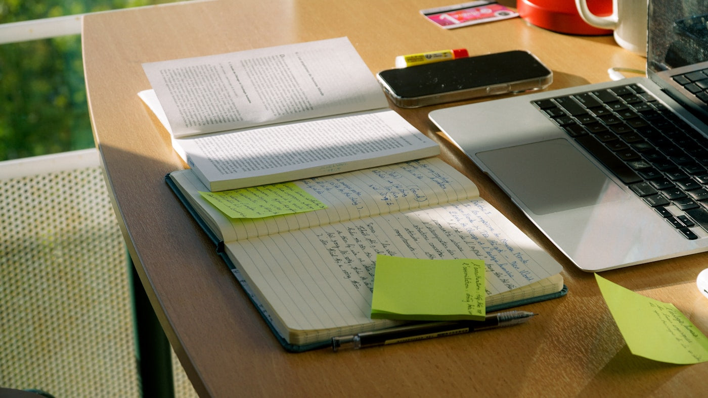 Notes and source materials arranged beside a laptop